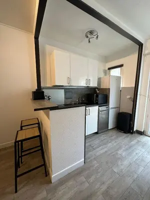 a kitchen with white cabinets and a counter top at Studio cosy avec balcon - Tramway au pied, proche centre in Nice
