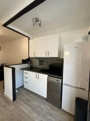 a kitchen with white cabinets and a refrigerator at Studio cosy avec balcon - Tramway au pied, proche centre in Nice