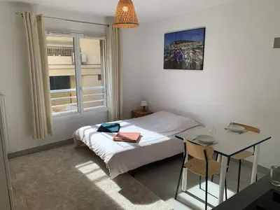 a bedroom with a bed and a table and a window at Joli studio, quartier du port in Nice