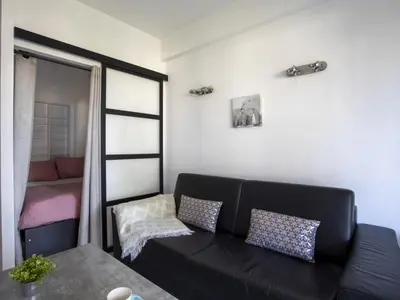 a living room with a black couch and a window at Apartment Le Persépolis by Interhome in Cagnes-sur-Mer