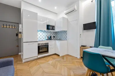 a kitchen with white cabinets and a table and chairs at Nice Renting - VERDUN - Designer Cocoon Massena Calm Air Conditioning in Nice