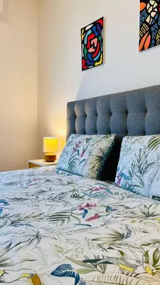 a bedroom with a bed with a blue head board at Azure Horizons Seaside Escape in Beaulieu-sur-Mer