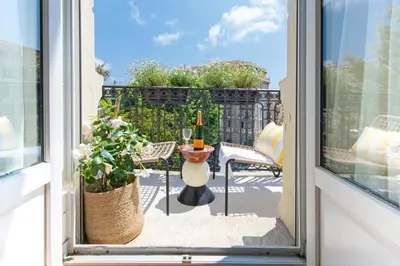 an open window with a table with a bottle of wine on a balcony at Sumptuous Art Deco Apartment - 6 People in Nice