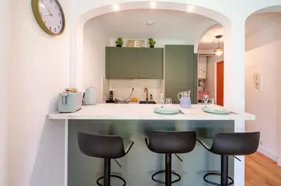 a kitchen with a counter with two stools and a counter top at Studio Jardin Parking et Clim in Nice