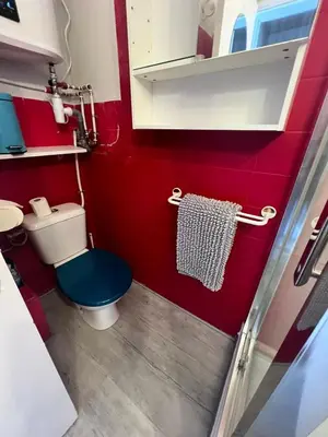 a small bathroom with a blue toilet and red walls at Studio à 5min de la plage in Nice