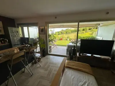 a living room with a television and a desk with a desk at Spacieux appartement, Jardin, vue mer, calme in Nice