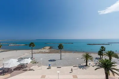 a view of a beach with palm trees and the ocean at Sea View- Beach- Chic & Air-Conditioned in Saint-Laurent-du-Var