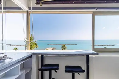 a kitchen with two stools at a counter with a view of the ocean at Sea View- Beach- Chic & Air-Conditioned in Saint-Laurent-du-Var