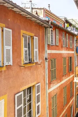 an orange building with white shuttered windows at La Vila-Vielha in Nice