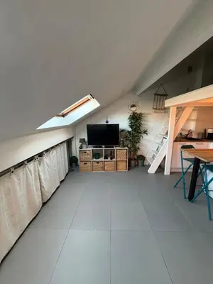an attic room with a flat screen tv and a table at Cosy Rooftop Studio Nice Centre in Nice