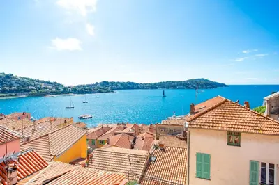 a view of the water and roofs of a town at #50 Contesso Duplex -1BDR, Sea View Terrace & AC in Villefranche-sur-Mer