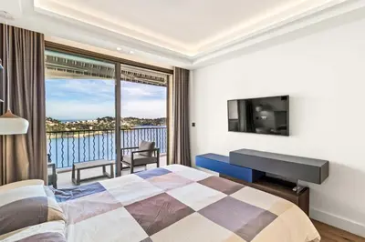 a bedroom with a bed and a balcony with a television at Magnifique appartement avec vue mer époustouflante in Villefranche-sur-Mer