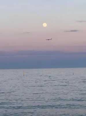 a plane flying over the ocean with the moon in the sky at F1 Cozy, 150m de la mer in Cagnes-sur-Mer