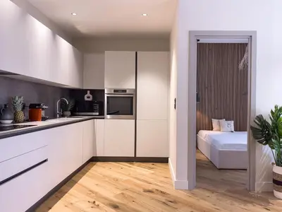 a kitchen with white cabinets and a bed at Appartement Niçois - 3 Pièces au Centre in Nice