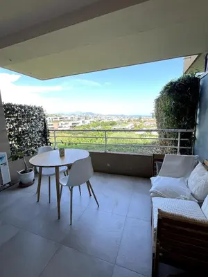 a patio with a table and chairs on a balcony at Appartement calme vue mer in Saint-Laurent-du-Var