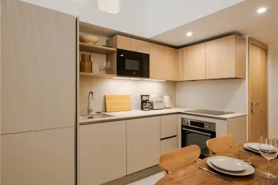 a kitchen with white cabinets and a wooden table at KALLISTE - NEW AC- Old town-Walk to everything - Beach- Restaurants-Supermarkets in Nice