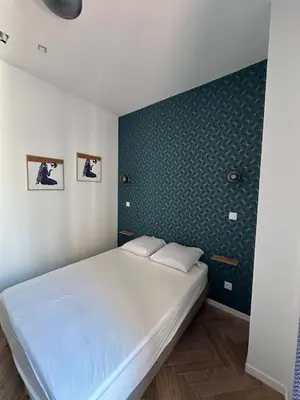 a white bed in a room with a green wall at MOON 21 in Nice