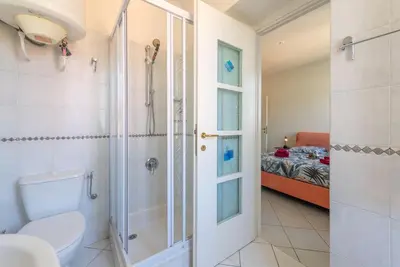a bathroom with a toilet and a shower and a bed at Beaulieu Garden Apartment in Beaulieu-sur-Mer