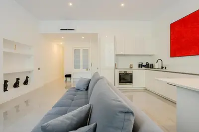 a living room with a blue couch and a kitchen at Paganini 3bd Apartment in Nice