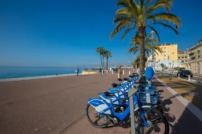 a row of blue bikes parked next to the beach at Capitol Close To The Beach - Happy Rentals in Nice