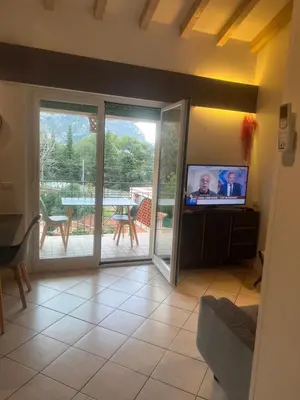 a living room with a sliding glass door and a television at Cosy studio piscine eze bord de mer in Èze
