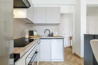 a kitchen with white cabinets and a sink at Wide & Cozy 1 Bdr Downtown in Nice