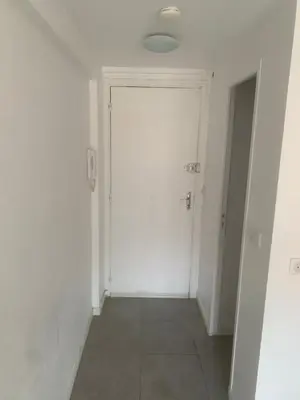 a hallway with a white door and a tile floor at studio 30m2 in Nice