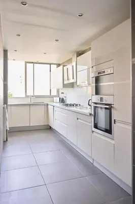 a white kitchen with white cabinets and appliances at Appartement Moderne 4 pièces Nice-Ouest in Nice
