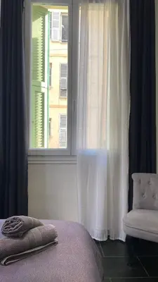a bedroom with a window and a bed and a chair at République in Nice