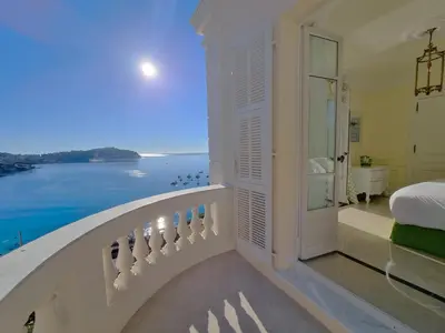 a bedroom with a balcony with a view of the ocean at Villa Soleil Riviera in Villefranche-sur-Mer