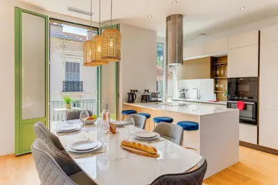 a kitchen with a white table and chairs and a kitchen with a counter at 33 MARINONI AP4438 by Riviera Holiday Homes in Beaulieu-sur-Mer