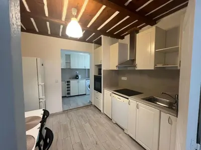 a large kitchen with white cabinets and a table at Katy in Nice