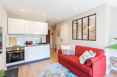 a living room with a red couch and a kitchen at Appartement cosy lumineux avec balcon in Nice