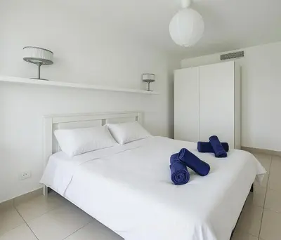 a white bed with two blue pillows on it at Spacieux T2 à 150m Des Plages in Cagnes-sur-Mer