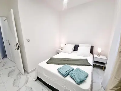 a white bedroom with a bed with two towels on it at Spacious Family Apartment Near Sea - Nice in Nice