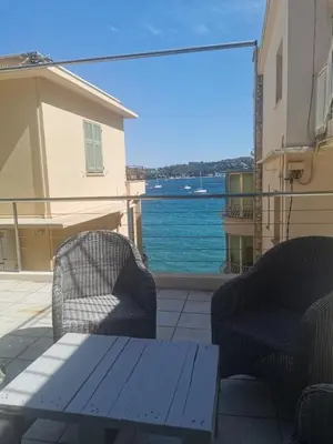 two chairs and a table on a balcony with a view of the water at Villa Ninette avec rooftop in Villefranche-sur-Mer