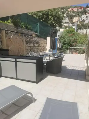 a patio with a table and chairs and a stone wall at Villa Ninette avec rooftop in Villefranche-sur-Mer