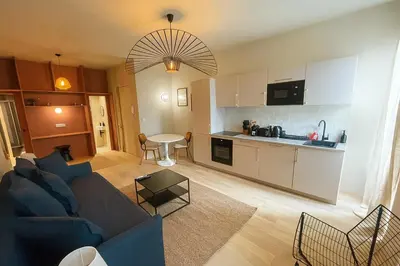 a living room with a blue couch and a kitchen at Central- walk to Massena & Beach in Nice