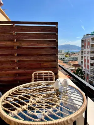 a rattan table with two birds sitting on it on a balcony at TheNiceTerrace in Nice