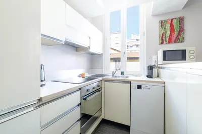 a white kitchen with white cabinets and a window at MY CASA - FRANCE 82 - 2 rooms -1 min from the Sea - Parking in Nice