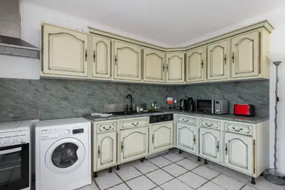 a kitchen with yellow cabinets and a washer and dryer at Villa les Oliviers in La Gaude