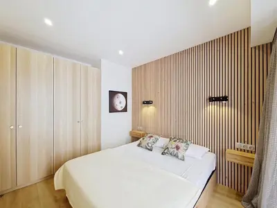 a bedroom with a white bed and a wooden wall at Nestor&Jeeves - MAYA TERRASSE - Centre ville in Nice