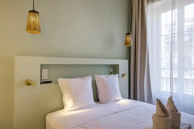 a bedroom with a bed with white sheets and a window at Grand appartement Centre de Nice in Nice