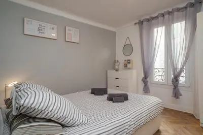 a white bedroom with a bed and a window at Le Chic, appartement plein centre avec Climatisation in Nice