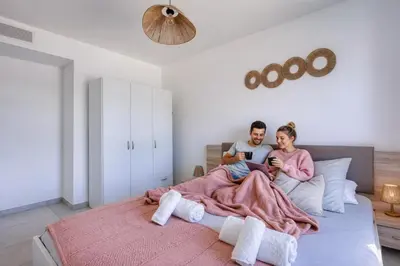 a man and woman sitting on a bed looking at their cell phones at Chez Valentina et Alexandre Port et plages à pied in Saint-Laurent-du-Var
