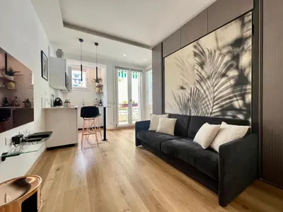 a living room with a black couch and a kitchen at Oasis Azur 1 min from the beach in Nice
