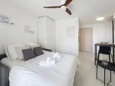 a bedroom with a large white bed with a ceiling fan at Studio Neuf avec Terrasse et Aperçu Mer in Nice