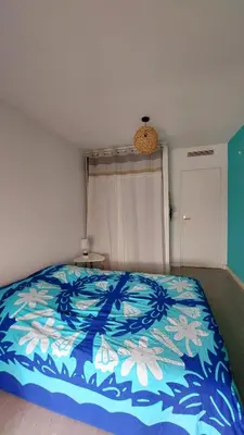 a bedroom with a bed with a blue and white blanket at Apartment with balcony 5 minutes walk from the sea in Cagnes-sur-Mer