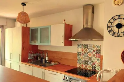 a kitchen with white cabinets and a clock on the wall at Apartment with balcony 5 minutes walk from the sea in Cagnes-sur-Mer