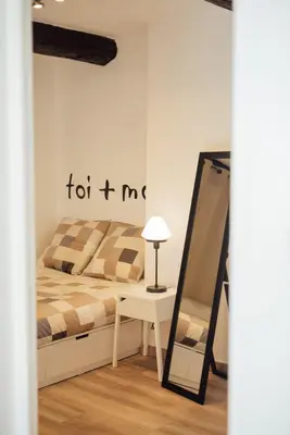 a bedroom with a bed and a table and a mirror at L'Authentic, charme dans la vieille ville avec climatisation in Nice